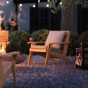 Lite modern adirondack stol framför en eldstad i en trägård